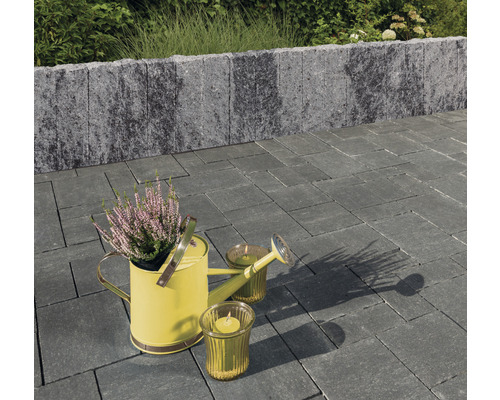 Gartenanlage mit Pflastersteinen, Mauer, Gießkanne und Kerzen