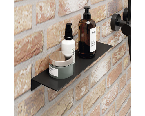 Schwarzes Wandregal im Badezimmer mit Pflegeprodukten auf einem Backsteinuntergrund.