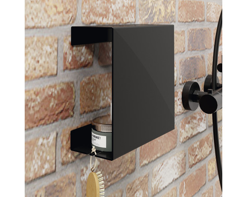 Schwarzes Duschregal an einer Ziegelwand mit einer Bürste und einer Dose