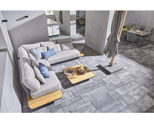 Außenbereich mit Ecksofa, Tisch, Feuerstelle, Sonnenschirm und Gartentisch mit Stühlen auf Pflastersteinen