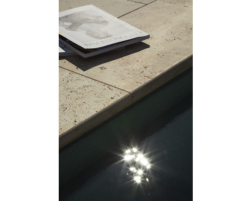 Zeitschriften auf einer Poolumrandung neben einem Swimmingpool