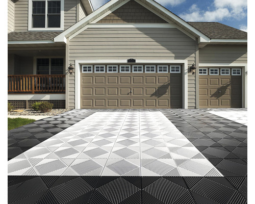 Auffahrt mit ineinandergreifenden Fliesen vor einem Wohnhaus mit zwei Garagentoren