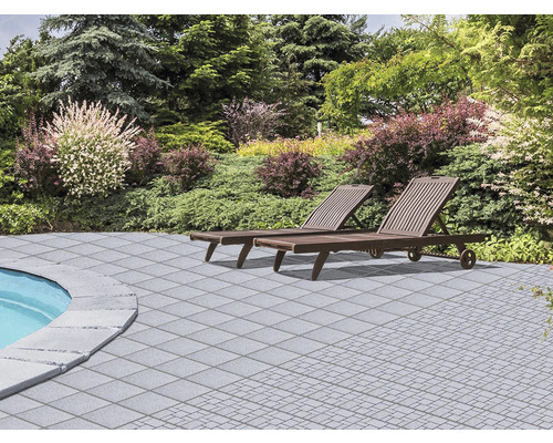 Terrasse mit Steinplatten und zwei Liegestühlen im Garten.