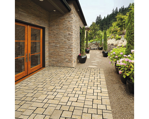 Außenbereich mit Pflastersteinen, einer Hauswand mit Steinverkleidung und einem Gartenweg