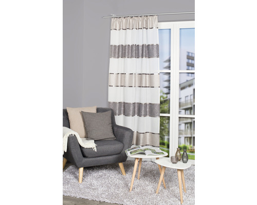 Wohnzimmer mit Sessel, Tisch und gestreifter Gardine