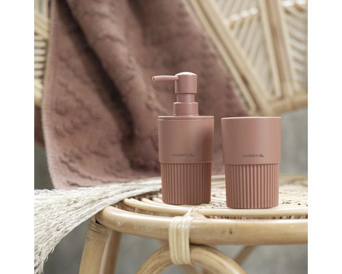 Seifenspender und Zahnputzbecher aus Kunststoff auf einem Rattanhocker