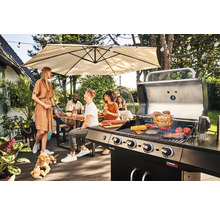 Gruppe von Freunden grillt und entspannt auf der Terrasse unter einem Sonnenschirm, wobei ein Gasgrill und Gartenmöbel zu sehen sind