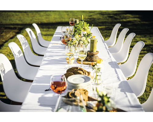 Gedeckter Esstisch mit weißen Stühlen im Freien