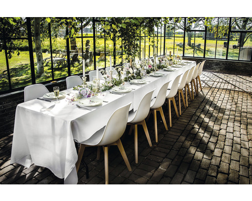 Gedeckter Tisch mit Stühlen in heller, geräumiger Umgebung.