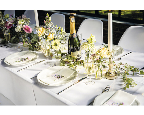 Gedeckter Tisch mit Tellern, Besteck, Gläsern, Blumen, Kerzen und einer Flasche Sekt für eine Feier