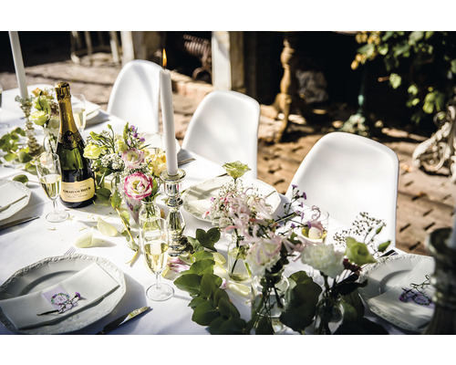 Festlich gedeckter Tisch mit Champagner, Kerzen und Blumen für eine Feier