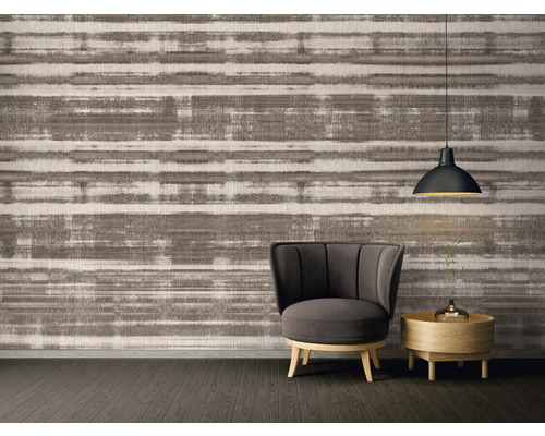 Interieuransicht mit gemusterter Tapete, Sessel, Beistelltisch und Pendelleuchte.