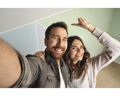 Ein Paar posiert vor einer Wand mit geometrischen Mustern.