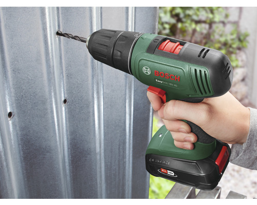 Eine Person bohrt mit einem Akkuschrauber ein Loch in ein Metallblech. Bosch Logo.