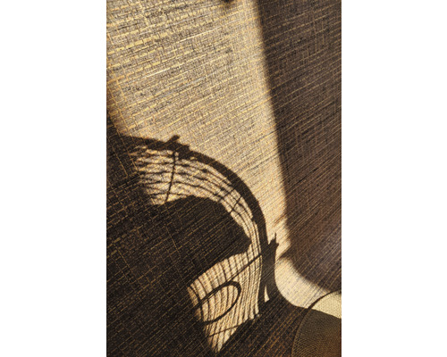 Nahaufnahme eines texturierten Vorhangs mit dem Schatten eines Korbstuhls