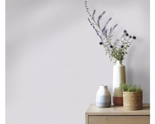 Wand mit Vliestapete und Blumenarrangements in Vasen auf einem Holzschrank