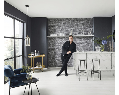 Heller Raum mit Bar, Hockern, Sessel, Beistelltisch und einem Mann