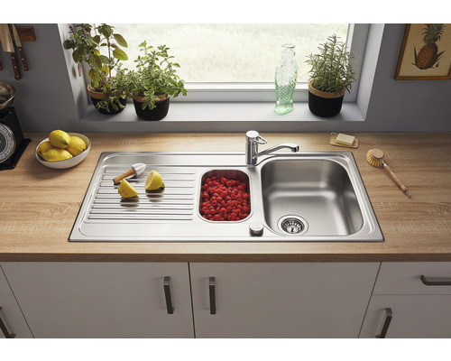 Spüle aus Edelstahl mit Abtropffläche und Becken voller Himbeeren auf einer Küchentheke