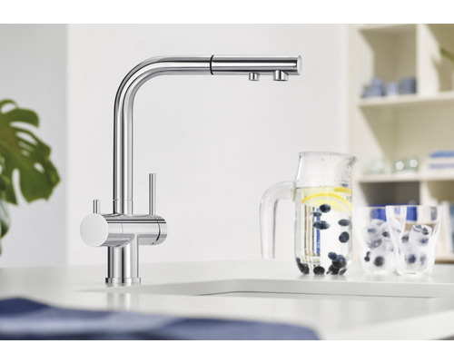 Küchenarmatur aus Metall mit hohem Auslauf und Ausziehbrause neben einem Krug mit Wasser.