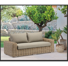 Gartenlandschaft mit einem Rattansofa und Polsterkissen