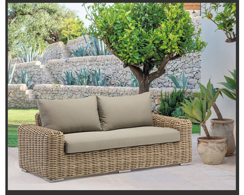 Gartenlandschaft mit einem Rattansofa und Polsterkissen