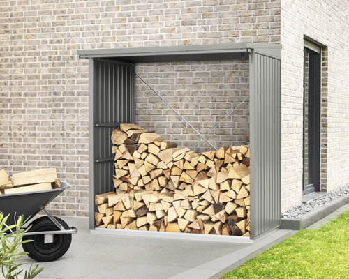 Holzlager aus Metall mit Holzscheiten vor einer Ziegelmauer