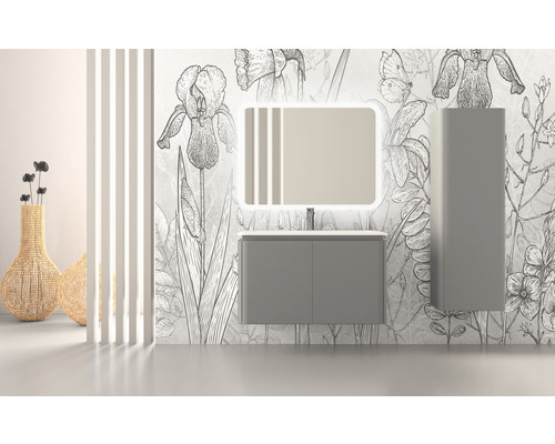 Badezimmer mit Waschtischunterschrank, beleuchtetem Spiegel und Hochschrank vor einer Wand mit Blumenmuster