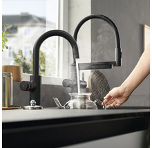 Küchenszene mit schwarzem Wasserhahn, der Wasser in eine Teekanne gießt