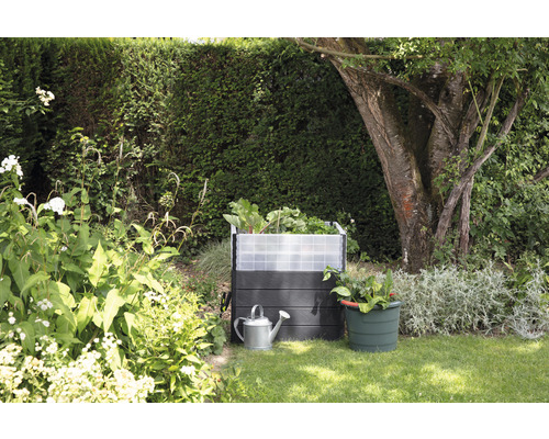 Hochbeet mit Bewässerungskanne und Pflanztopf im Garten.