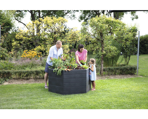 Familie beim Bepflanzen eines Hochbeets im Garten.