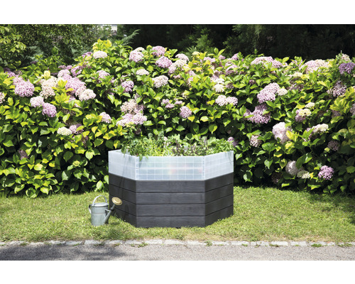 Hochbeet aus Holz mit Pflanzen und Gießkanne im Garten