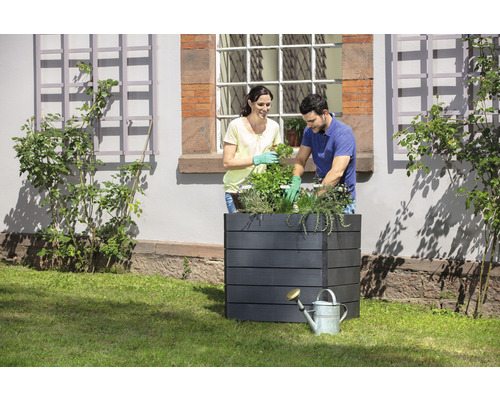 Szene mit einem Pflanzkasten und zwei Personen, die Pflanzen einsetzen.