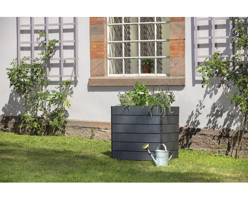 Quadratischer Pflanzkasten aus Holz mit Bewässerungskanne im Garten