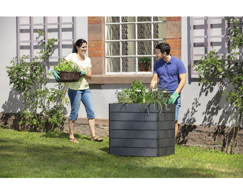 Gartenbild mit einem Paar beim Bepflanzen eines Hochbeetes mit Kräutern.