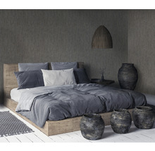 Schlafzimmer mit Holzbett, Textilien, Lampe und dekorativen Vasen