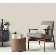 Beige Vliestapete in einem Wohnzimmer mit Sessel, Tisch und Dekoration