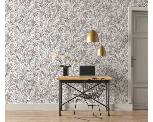 Büro mit Schreibtisch, Stuhl, Laptop, goldenen Lampen und Tapete mit Pflanzenmuster