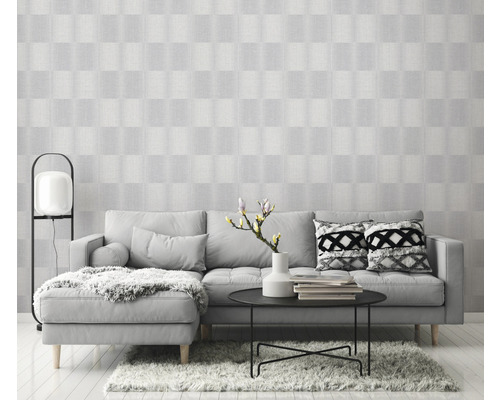 Helles Wohnzimmer mit grauer Couch, Tisch und gemusterter Tapete für eine freundliche Atmosphäre.