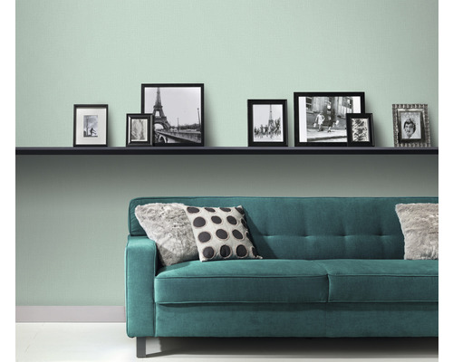 Wohnzimmer mit Regal, Bildern und grünem Sofa