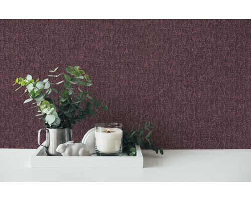 Dekoratives Zimmer mit gemusterter Tapete, Kerze, Pflanze und Dekofigur