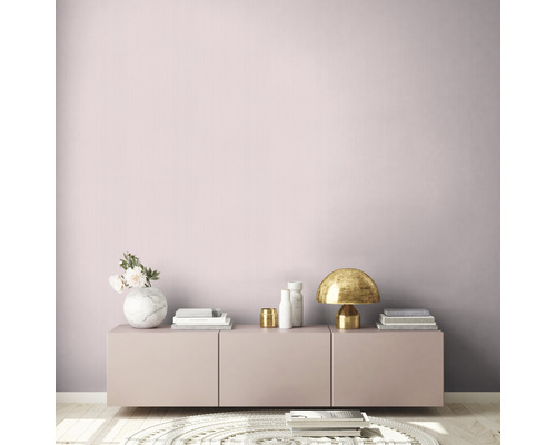 Helles Zimmer mit rosa Wand, Kommode, Tischlampe und Dekorationsartikeln