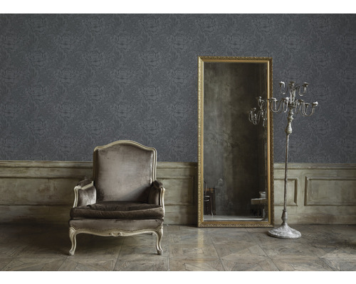 Wohnraum mit floral gemusterter Tapete, Sessel, Spiegel und Kerzenständer