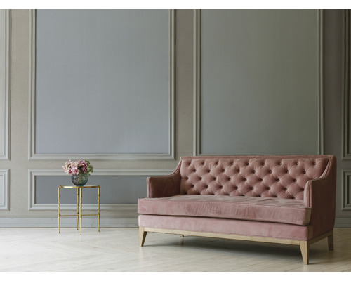 Wohnzimmer mit Wandpaneelen, Sofa mit Knopfheftung und Beistelltisch mit Blumenstrauß
