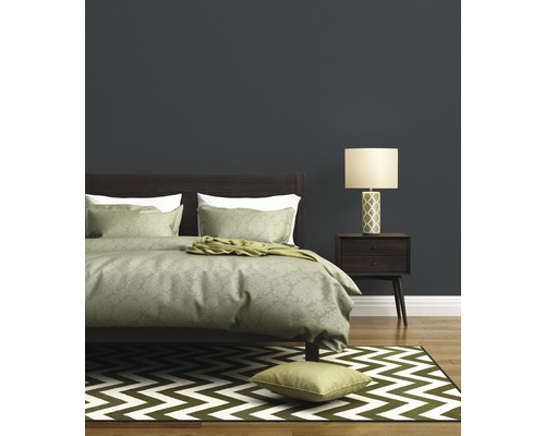 Schlafzimmer mit Bett, Nachttischlampe und Teppich mit Zickzackmuster