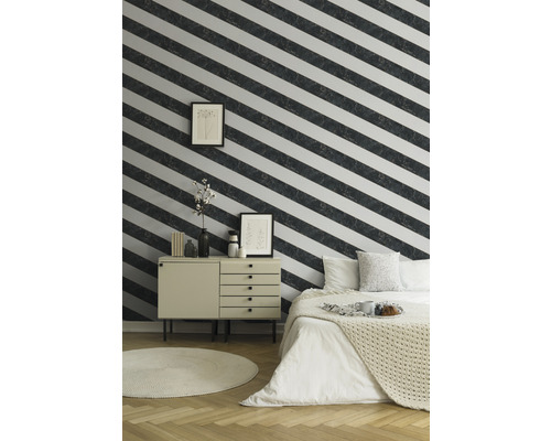 Schlafzimmer mit Bett, Kommode, Teppich und Wand mit gestreifter Tapete