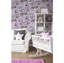 Kinderzimmer mit weißer Wiege, Regal und Sofa vor einer Tapete mit Tiermotiven