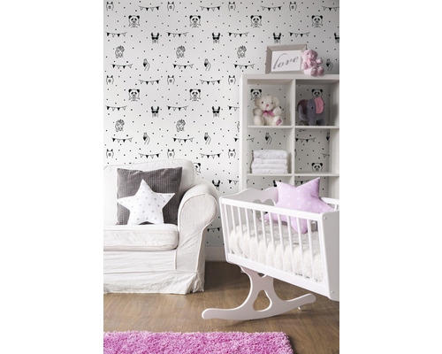 Kinderzimmer mit weißer Wiege, Sofa und Regal vor einer Tapete mit Tiermotiven.