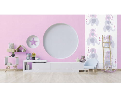 Helles Kinderzimmer mit rosa Wand, weißem Schrank, Stuhl und Elefantentapete