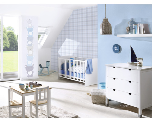 Ein Kinderzimmer mit einem Kinderbett, einer Kommode, einem Tisch und Stühlen.
