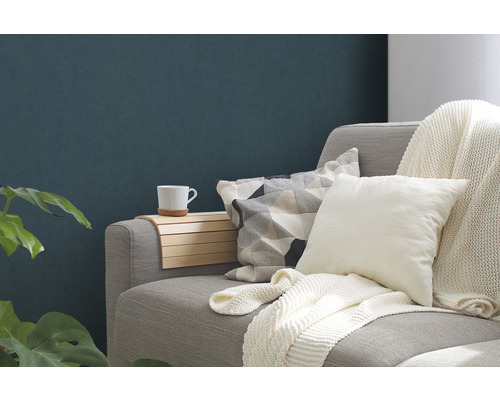 Nahaufnahme eines Sofas mit Kissen, Decke, Armlehnenauflage und Tasse.